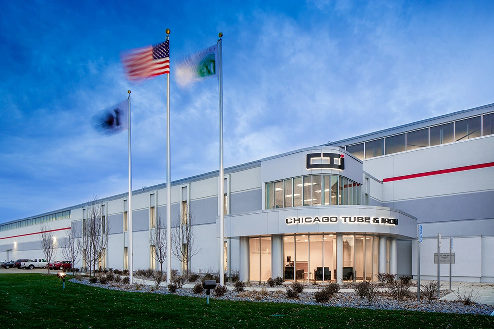 exterior of Chicago Tube & Iron industrial building with three flag poles in front